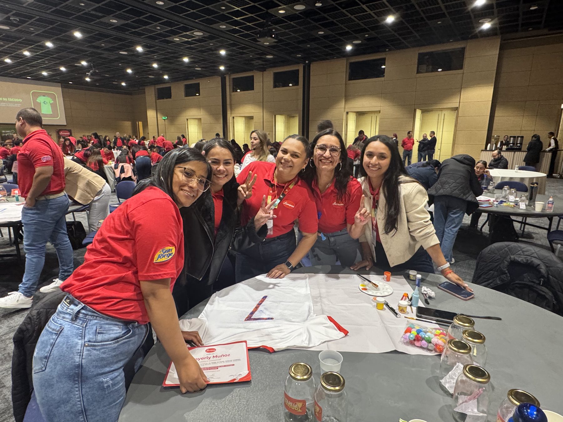 Participantes sonriendo alrededor de una mesa de trabajo en una convención